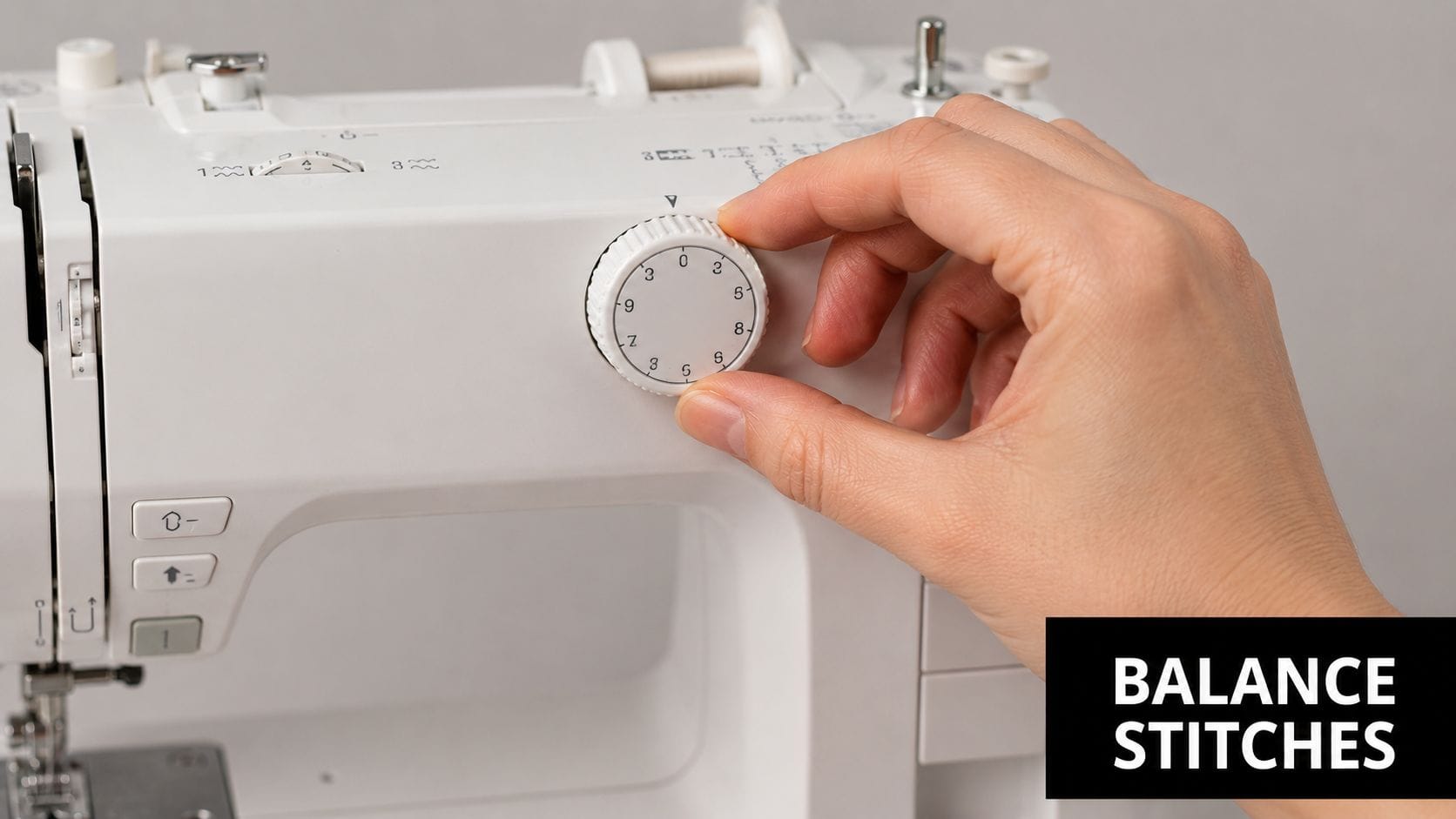 A close-up view of a hand adjusting the stitch balance dial on a modern white sewing machine.