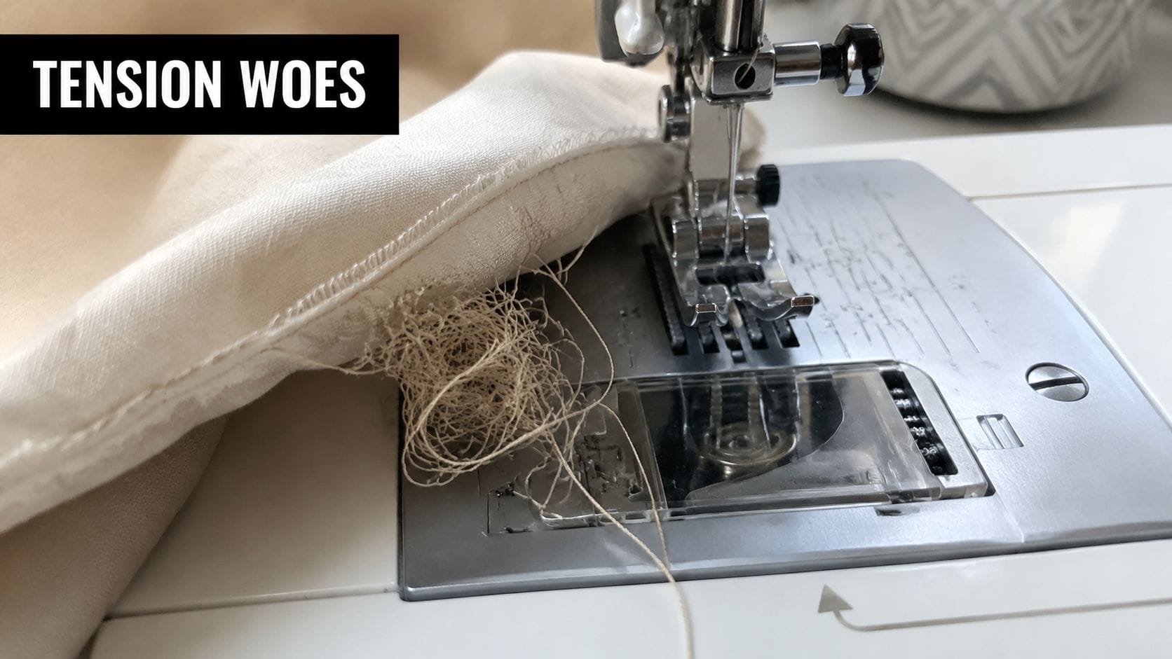 A sewing machine experiencing thread bunching and tension issues on a piece of light beige fabric.